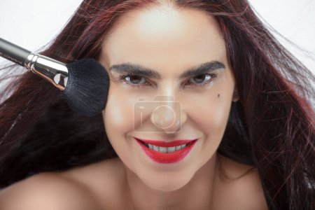 Photo for Extreme close-up of an adult woman applying makeup with a brush in her hand - Royalty Free Image