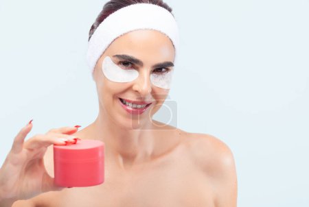Téléchargez les photos : Femme souriante tout en tenant un produit de soins de la peau dans sa main - en image libre de droit