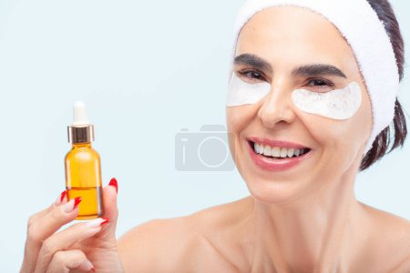 Photo for Senior woman smiling while holding a skincare product bottle in her hand - Royalty Free Image
