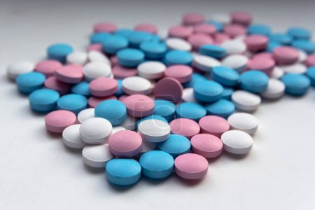 Auf dem Tisch liegen weiße, blaue und rosa Tabletten. Medizin