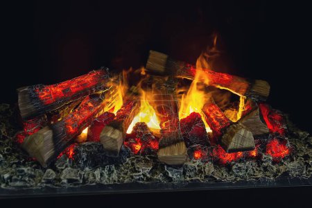 Die Holzscheite des Kamins brennen lichterloh. Künstlicher dekorativer Kamin mit Imitation von Feuer.