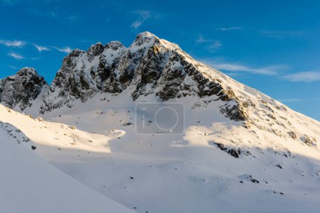 Téléchargez les photos : Le pic (Kozi vrch, Kozi Wierch) illuminé par les rayons du soleil couchant en hiver dans les montagnes polonaises Tatra. - en image libre de droit