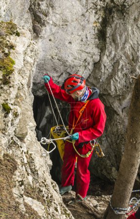 Téléchargez les photos : Koscielisko, Pologne - 03 mars 2024 : Un spéléologue se préparant à entrer dans la grotte Czarna (noire) dans les montagnes Tatra, à l'aide d'une corde. Pologne. - en image libre de droit