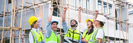 Foto de Group of contractors, engineers and formats in safety vests with helmets hands up to work together to successfully complete a construction project on construction site. cooperation and success concept - Imagen libre de derechos