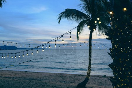 Foto de Bombillas en la decoración de alambre de cuerda en el festival del evento de fiesta en la playa al atardecer. Fondo de vacaciones al aire libre. Copiar espacio - Imagen libre de derechos