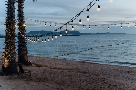 Foto de Bombillas en la decoración de alambre de cuerda en el festival del evento de fiesta en la playa al atardecer. Fondo de vacaciones al aire libre. Copiar espacio - Imagen libre de derechos