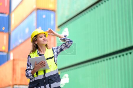 Photo for Engineer women wear yellow helmets and reflection shirts working on tablet computers to check inventory details of containers box. Inspector or Safety Supervisor in Container Terminal - Royalty Free Image
