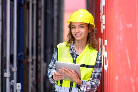 Las mujeres ingenieras usan cascos amarillos y camisas reflectantes que trabajan en tabletas para verificar los detalles del inventario de la caja de contenedores. Inspector o Supervisor de Seguridad en Terminal de Contenedores