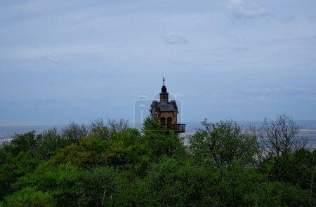 Foto de Pequeña torre de piedra con balcón se encuentra en la cima de la colina con vistas a un vasto paisaje verde. - Imagen libre de derechos