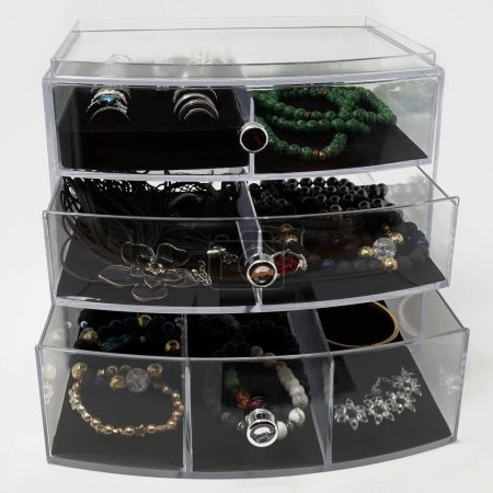 Photo for Acrylic glass box with glitter and glass jewellery. One malachite necklace is in the upper compartment - Royalty Free Image