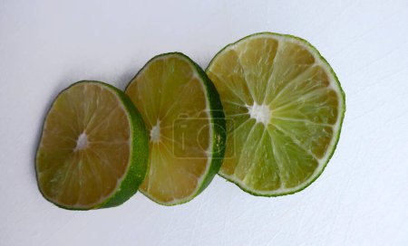 Photo for Persian lime fruit slices on an white cutting board. Lime is a citrus fruit. This lime is a cross between key lime and lemon - Royalty Free Image