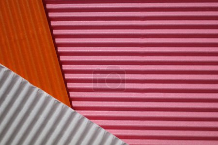 Photo for Horizontally and diagonally ribbed cardboard with the colors pink, white,  orange. Meant as background - Royalty Free Image