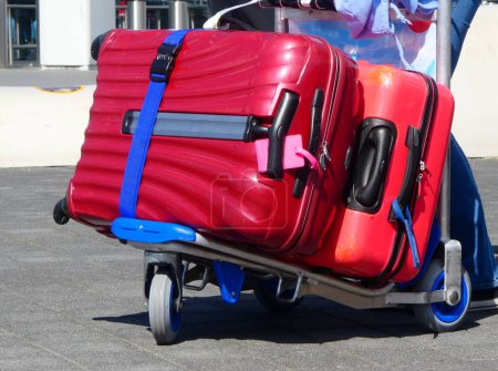 Téléchargez les photos : Un chariot à bagages avec deux valises rouges - en image libre de droit