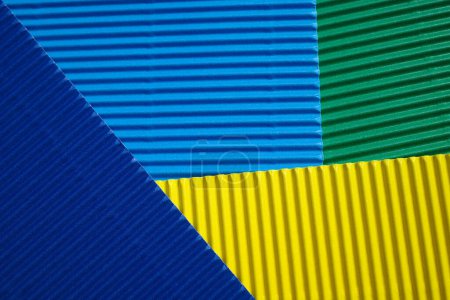 Photo for Horizontally and diagonally ribbed cardboard with the colors green, blue and yellow. Meant as background - Royalty Free Image