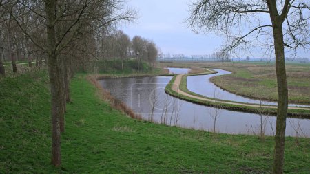 Vista del pólder de invierno en un canal con un carril bici creado en el centro en Sluis, Flandes Zelandés, Países Bajos