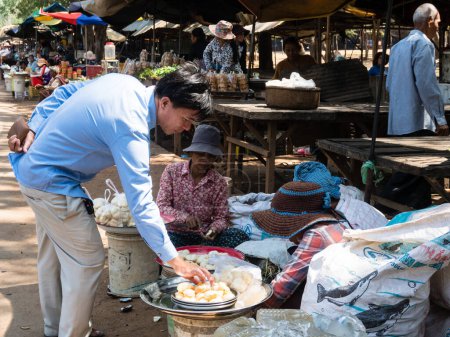 Photo for Oudongk, Cambodia - February 12, 2017: Man buying palmyra palm fruit at a street market in Oudong - Royalty Free Image