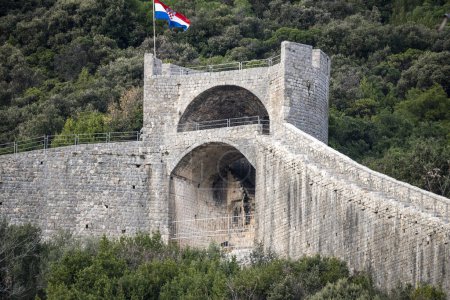 Famous tower and defence walls in the town of Ston on Peljesac peninsula, Croatia, set of famous TV show with knights and dragons with croatian flag swaying on the top