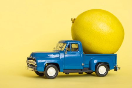  Jouet voiture bleu ramassage et citron sur fond jaune, livraison de légumes et fruits, vitamines en automne, hiver et printemps, mise au point sélective