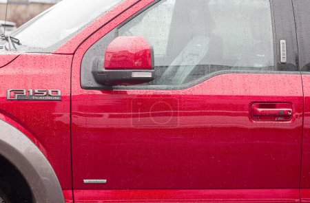 Téléchargez les photos : Lviv, Ukraine - 12 24 2022 : Affichage rouge de Ford F-150 dans un concessionnaire automobile. Ford F150 disponible en fragment de platine VUS Ford F150 Platine stationné par temps pluvieux - en image libre de droit