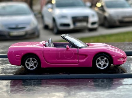 Foto de Lviv Ukraine - 04 01 2023:Pink car toy cabriolet on the city street, car for girls, speed and comfort in a luxury car, selective focus - Imagen libre de derechos