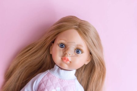 Muñeca de plástico con ojos azules y pelo rubio retrato de cerca, juguetes modernos muñeca de vinilo español, enfoque selectivo