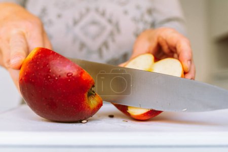 Téléchargez les photos : Couper les pommes en tranches pour un séchage ultérieur. Mains féminines à l'aide d'un couteau de cuisine couper de grandes pommes mûres en tranches étalées sur une plaque à pâtisserie - en image libre de droit