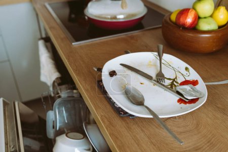vaisselle sale usagée sur comptoir de cuisine en bois, avec lave-vaisselle intégré. mobilier moderne, concept de nettoyage de cuisine
