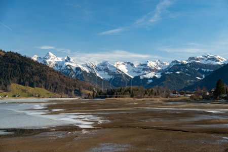 Photo for Einsiedeln area, Canton Schwyz, Switzerland, February 20, 2023 Stunning alpine scenery at the coast of the lake Sihlsee on a sunny winter day - Royalty Free Image