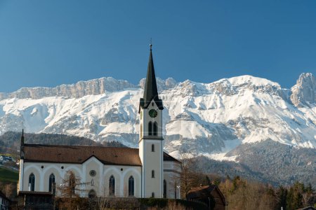 Photo for Gams, Canton Saint Gallen, Switzerland, February 7, 2023 Historic Saint Michael church on a little hill surrounded with beautiful snow covered mountains - Royalty Free Image