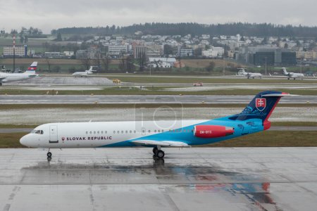 Photo for Zurich, Switzerland, January 17, 2024 OM-BYC Slovak Government Fokker 100 aircraft is taxiing through the rain during the world economic forum in Davos - Royalty Free Image