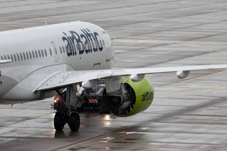 Foto de Zurich, Suiza, 17 de enero de 2024 YL-ABE Air Baltic Bombardier CS-300 o Airbus A220-300 son remolcados a lo largo del delantal en un día lluvioso - Imagen libre de derechos