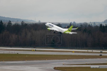 Foto de Zurich, Suiza, 17 de enero de 2024 YL-AAV Air Baltic Bombardier CS-300 o Airbus A220-300 salen de la pista 28 durante una ducha de lluvia - Imagen libre de derechos