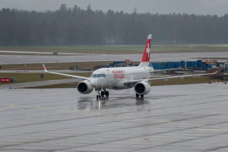 Foto de Zurich, Suiza, 17 de enero de 2024 HB-JBG Swiss Airbus A220-100 or Bombardier CS-100 aircraft is taxiing to the gate during a rain shower - Imagen libre de derechos