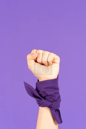 Closeup of raised fist of feminist activist isolated on purple background with copy space.