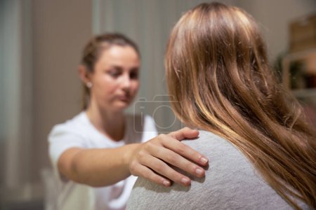 Closeup of helping hand on shoulder. Woman comforting sister at night.