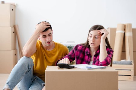 Worried young couple calculating expenses in their new home. Moving house and mortgage concept.