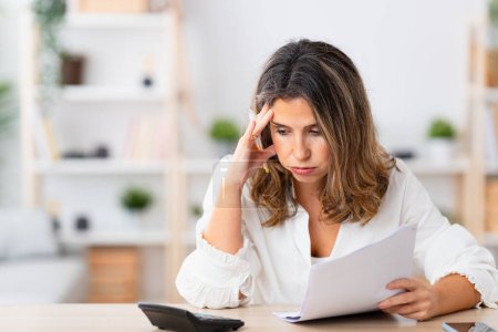 Mujer buscando estresado mientras se utiliza la calculadora para calcular las finanzas del hogar