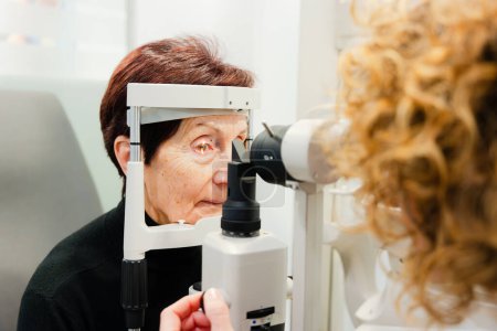 Elderly woman checking her vision using biomicroscopy machine in a clinic