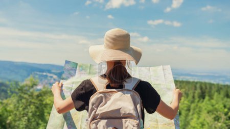 Photo for Young woman traveler with a backpack and a map on the background of mountains - Royalty Free Image
