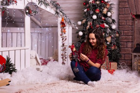Téléchargez les photos : Fille à Noël. Joyeuse femme joyeuse célébrant le nouvel an avec des cadeaux près de l'arbre de Noël
. - en image libre de droit