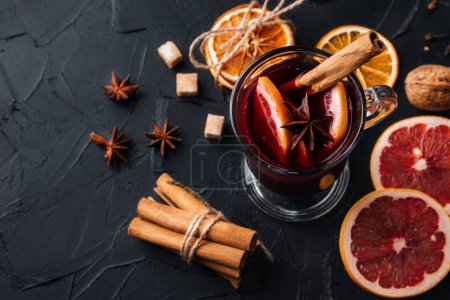 Photo for Making mulled wine at home. Cup on the table, near it are cinnamon, citrus fruits, dried oranges, star anise, cane sugar. - Royalty Free Image