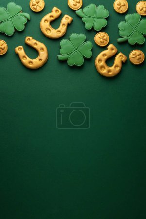 Téléchargez les photos : Vertical banner for St. Patrick's Day on green background. Coins, horseshoes, four-leaf clover as symbols of the holiday. Place for text. Gingerbread cookie items. - en image libre de droit