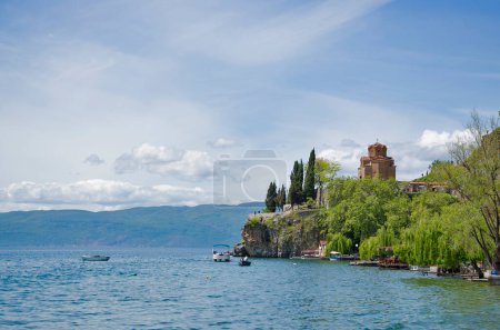 Impressionnante vue depuis le lac avec des bateaux arbre, pierres, plage, montagne sur ciel bleu clair