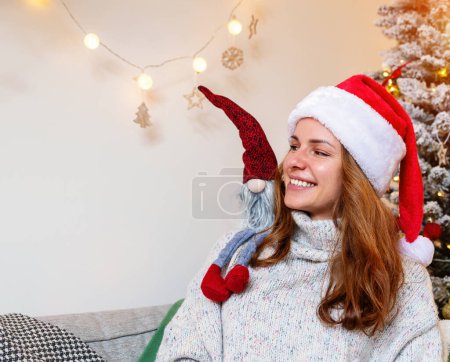 Photo for Childishness of adult people while Christmas. Young adult woman playing with kids toy gnomes. - Royalty Free Image