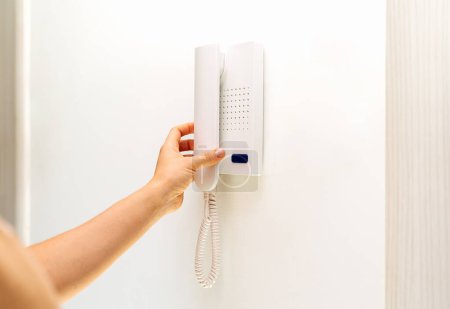 Foto de Persona femenina que usa un dispositivo de intercomunicación en su apartamento. - Imagen libre de derechos