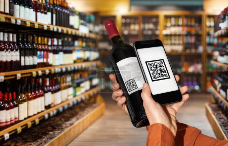 Foto de El cliente escanea el código qr en la botella de vino por teléfono inteligente en la tienda de licores. - Imagen libre de derechos