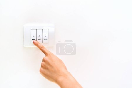 Female finger on light switch close-up.