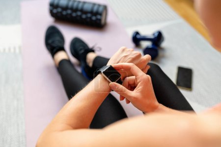 Sportliche Frau beim Workout mit ihrer Smartwatch. Fitness-Tracker. Tragbare Technologie