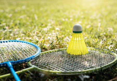 Téléchargez les photos : Deux raquettes de badminton et un volant jaune sur l'herbe verte. Loisirs et activités sportives d'été. - en image libre de droit