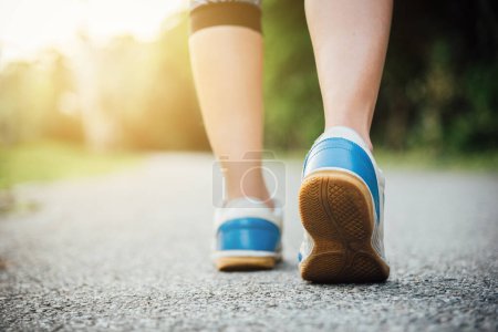 Téléchargez les photos : Femme en chaussures de course marchant sur le chemin un matin - en image libre de droit